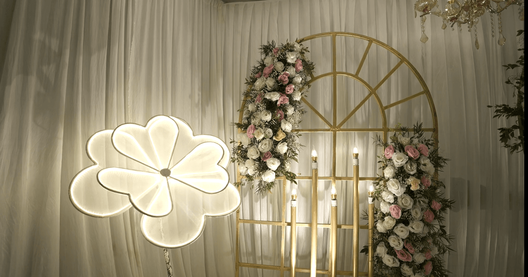 Luxury event stage design with a gold floral arch and chandeliers, Saudi Event Management